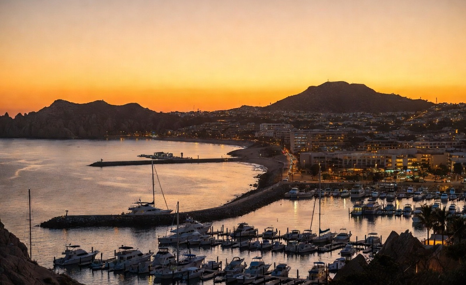 A marina at sunset with warm lights and moored boats.